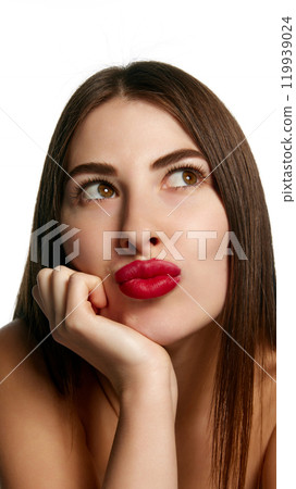 Pretty woman looks chic with red lipstick on lips, purses lips to make a kiss against white background. 119939024