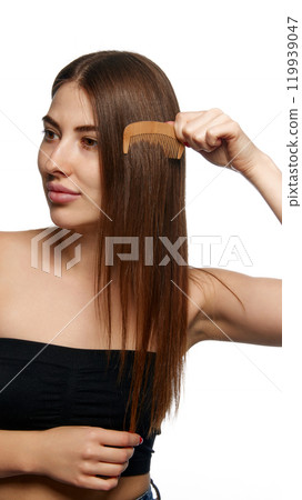 Woman brushing her hair with wooden comb, focusing on simple, natural hair care practices against white background. Woman brushing her hair with wooden comb, focusing on simple, natural hair care practices against white background. 119939047