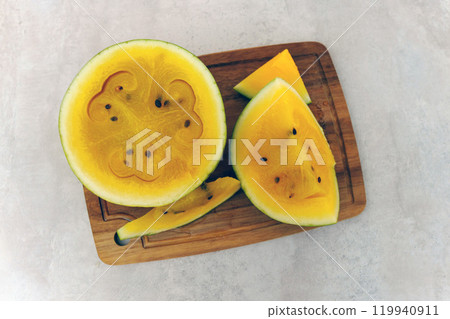Delightful yellow watermelon arranged elegantly on a wooden cutting board during a sunny afternoon gathering 119940911