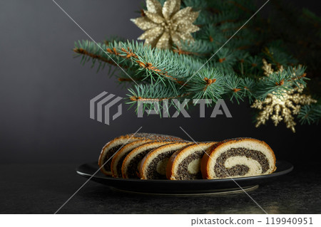 Poppy seed roll pieces on a background of Christmas tree. 119940951