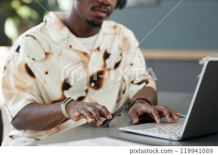 Close up of unrecognizable African American man playing with fingerboard fidget toy on desk while working with laptop in office, copy space Close up of unrecognizable African American man playing with fingerboard fidget toy on desk while working with laptop in office, copy space 119941089