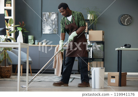 Full length side view of adult African American man mopping floors in office and enjoying Spring cleaning at workplace, copy space Full length side view of adult African American man mopping floors in office and enjoying Spring cleaning at workplace, copy space 119941176