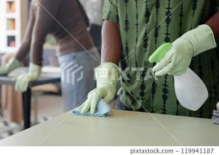 Close up of unrecognizable African American man cleaning table in office workplace and wearing rubber gloves, copy space Close up of unrecognizable African American man cleaning table in office workplace and wearing rubber gloves, copy space 119941187
