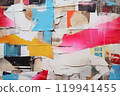 Urban Tapestry A Visual Symphony of Old Wrinkled Grunge Ripped Torn Placard Posters Background, Featuring Weathered Advertising Poster Pieces in White, Pink, Blue, and Yellow Colors on a Wall.. 119941455
