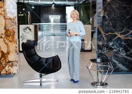 Confident Businesswoman Holding Tablet in Modern Office Setting 119941793