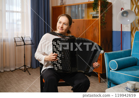 A middle-aged woman plays the accordion in a cozy living room during a sunny afternoon A middle-aged woman plays the accordion in a cozy living room during a sunny afternoon 119942659