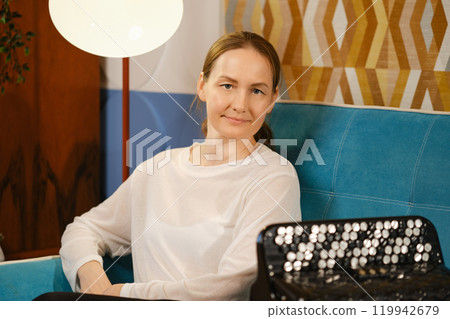A middle-aged woman relaxes on a blue couch in a cozy living room during an evening gathering A middle-aged woman relaxes on a blue couch in a cozy living room during an evening gathering 119942679