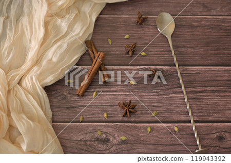 Close-up spicy spices and cinnamon on wooden table with spoon and cloth on background 119943392