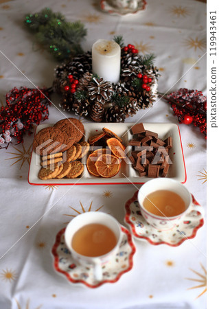 an elegantly set Christmas table, perfectly arranged for a delightful tea party featuring an assortment of cookies. Festive decorations, including seasonal tableware and beautiful centerpieces 119943461