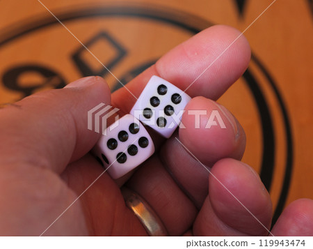 A hand shows two six-sided dice with black dots 119943474