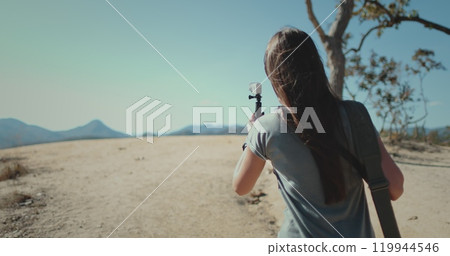 Travel blogger woman shooting on camera beautiful mountain landscape. Girl walk hold record on gopro, back view. Outdoor lifestyle travel on summer holiday vacation. Pai Canyon Chiang Mai , Thailand. 119944546
