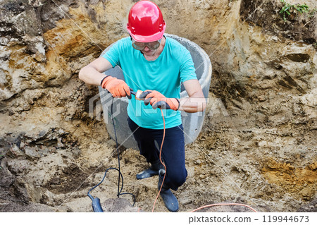 Worker inserts an electrical appliance plug into an extension cord socket. 119944673