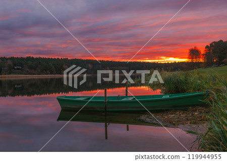 A Serene Sunset Over Calm Waters Featuring a Charming Green Boat Floating Gracefully. Birstonas, Lithuania A Serene Sunset Over Calm Waters Featuring a Charming Green Boat Floating Gracefully. Birstonas, Lithuania 119944955