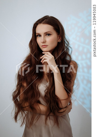 Woman with long brown hair posing for a photo on a white background. 119945083