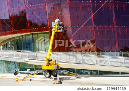 Glass facade cleaning works of a modern building using a modern telescopic boom lift with a basket 119945289