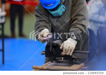 A craftsman filing a piece, removing burrs A craftsman filing a piece, removing burrs 119945559
