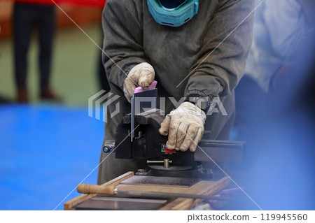 A craftsman filing a piece, removing burrs 119945560