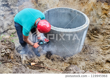 Angle grinder with diamond blade disc for concrete cutting is used during installation of septic tank. 119945968