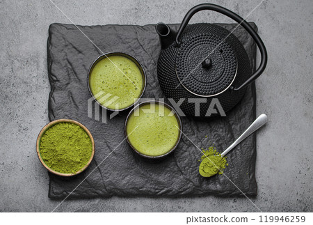 Matcha tea ceremony set with black iron teapot and two cups on black slate plate, traditional Japanese tea top view 119946259