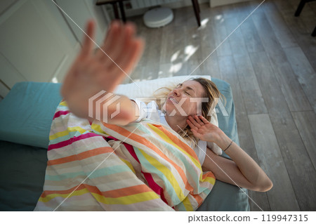 Relaxed woman closes hand and want to stay in bed in morning. Early wake up, sleep interruption Relaxed woman closes hand and want to stay in bed in morning. Early wake up, sleep interruption 119947315