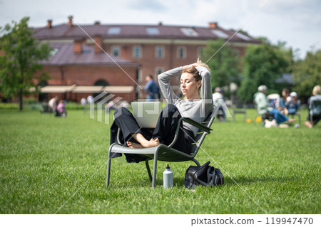 Relaxed woman rest with eyes closed while listen to lectures on laptop in park. Online school, study Relaxed woman rest with eyes closed while listen to lectures on laptop in park. Online school, study 119947470
