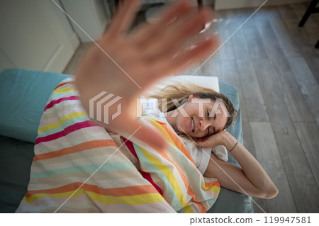 Portrait middle aged woman through palm smiling lying under blanket in bed awaked with good mood. Portrait middle aged woman through palm smiling lying under blanket in bed awaked with good mood. 119947581