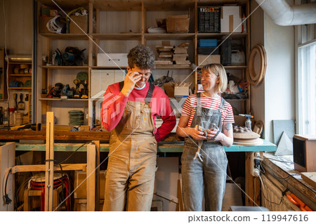 Cheerful carpenter couple goof off on break in workshop.Family business, teamwork, small business 119947616