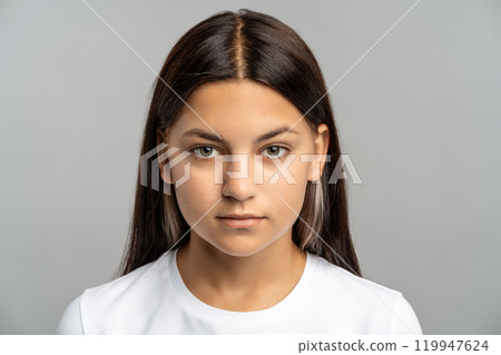 Confident teenage girl stares at camera on gray background, independence, Gen Z spirit, cool attitude Confident teenage girl stares at camera on gray background, independence, Gen Z spirit, cool attitude 119947624