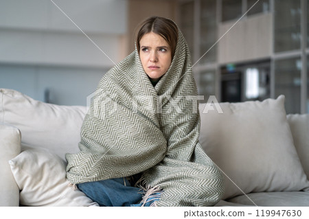 Lonely woman wrapped in blanket sit on couch, feel depression, sadness, emotional burnout, illness 119947630