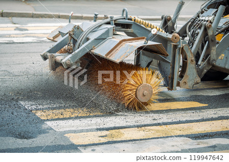 Tractor sweeps gravel from road after repair work at pedestrian cross. City renovation, maintenance Tractor sweeps gravel from road after repair work at pedestrian cross. City renovation, maintenance 119947642