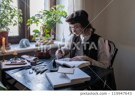 Engaged thoughtful female artist creates sketches using pen and brushes in notebook. Freelancer job Engaged thoughtful female artist creates sketches using pen and brushes in notebook. Freelancer job 119947643