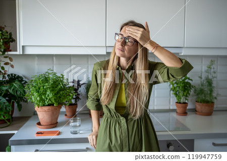 Exhausted middle aged blonde woman feels headache dizziness touching head with closed eyes at home. 119947759