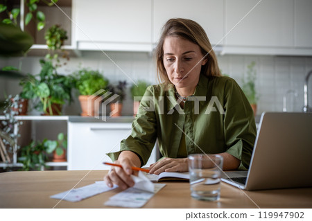 Freelance accountant analysing company invoices, verifying bills, checking income, savings at home 119947902