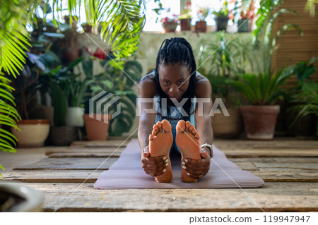 Athletic african american woman do flexibility exercise warm up muscles legs stretching back at home 119947947