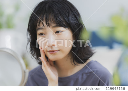 一位年輕女子在房間裡穿著保養品 一位年輕女子在房間裡穿著保養品 119948136