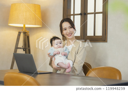 A woman in a suit holding a baby and working A woman in a suit holding a baby and working 119948239