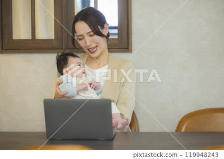 A woman in a suit holding a baby and working 119948243