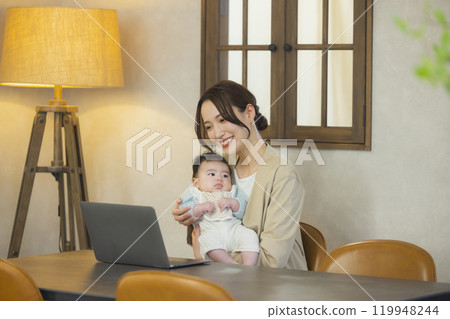 A woman in a suit holding a baby and working A woman in a suit holding a baby and working 119948244