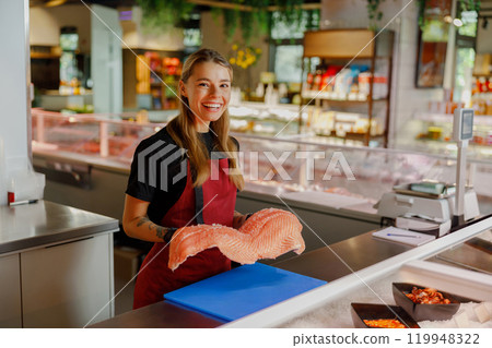 A Fresh Seafood Market Featuring a Smiling Fishmonger Who is Holding a Delicious Salmon 119948322