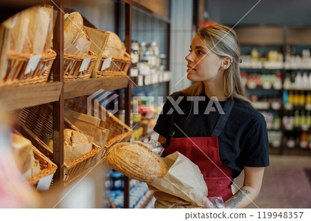 A Skilled Baker Proudly Displaying Freshly Made Artisan Bread in a Warm and Cozy Bakery A Skilled Baker Proudly Displaying Freshly Made Artisan Bread in a Warm and Cozy Bakery 119948357