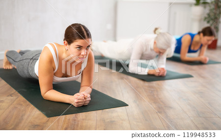 Young woman practicing plank pose in yoga studio 119948533