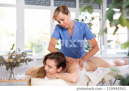 Relaxation. Masseur doing massage on woman body in spa salon. Beauty treatment concept 119948561