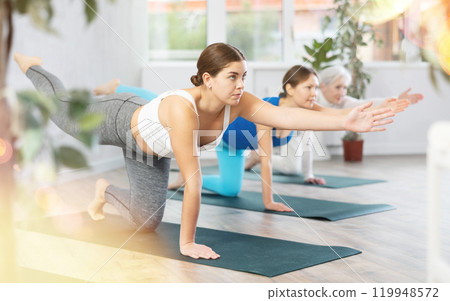 Concentrated girl doing Dandayamana Bharmanasana in yoga studio 119948572