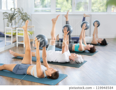 Young girl practicing Pilates with stability ball in group class 119948584