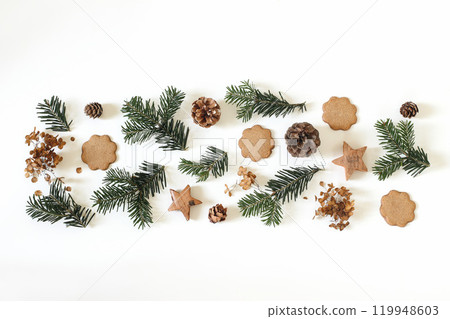 Christmas floral pattern. Winter composition. Green fir tree branches, gingerbread cookies, pine cones. Wooden stars isolated on white table background. Festive decorative frame banner. Flat lay, top. 119948603