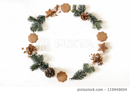 Christmas wreath isolated on white background. Advent circle floral composition. Christmas tree fir branches, pine cones, gingerbread cookies. Dry flowers. Winter decoration banner. Flat lay, top view 119948604