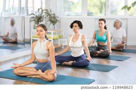 Young woman doing yoga in group in studio 119948623