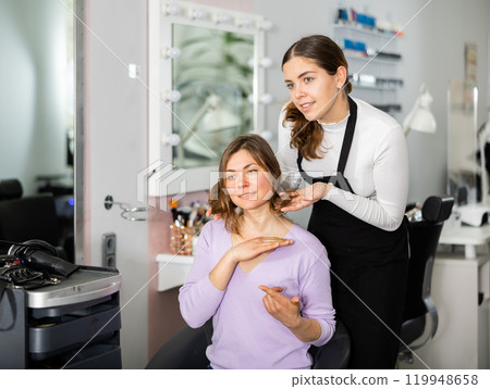 Hairdresser is discussing a haircut with a female client Hairdresser is discussing a haircut with a female client 119948658