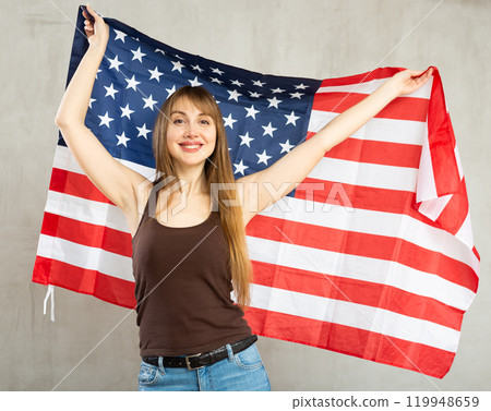 Cheerful woman posing with flag of United States in studio Cheerful woman posing with flag of United States in studio 119948659