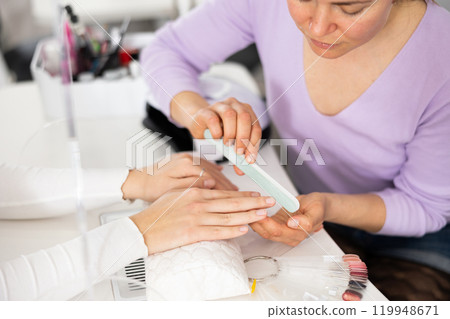 Woman hands, with which the manicure master files nails Woman hands, with which the manicure master files nails 119948671